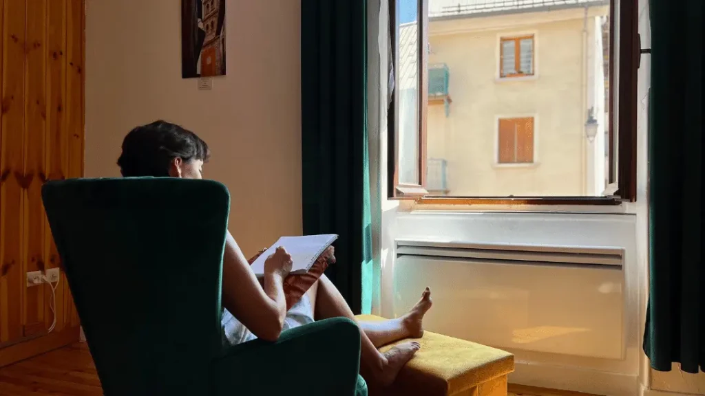 Woman writing next to a window in France. Housesitting