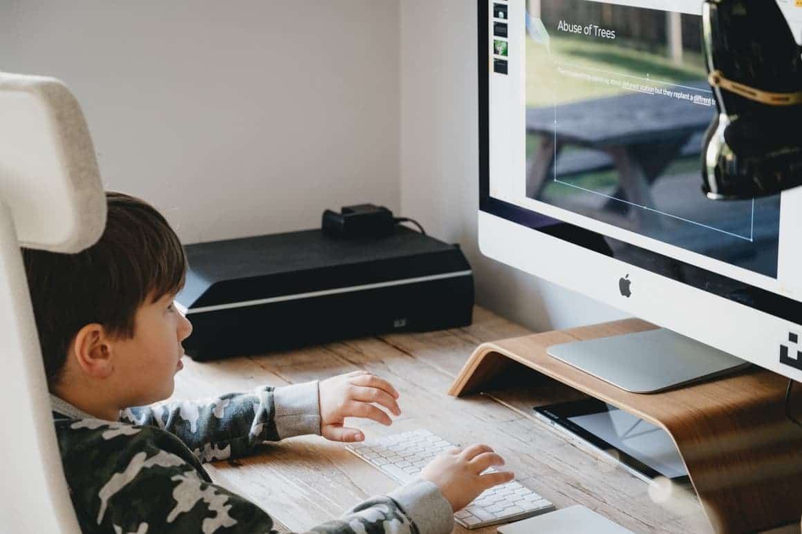 Boy playing on computer while homeschooling and his parent is working full time