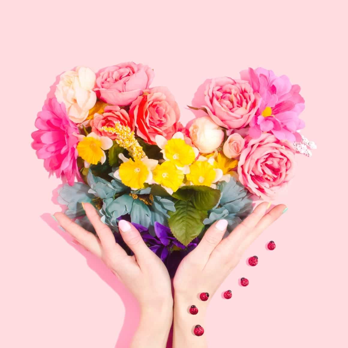 A heart of flowers being held by a womans hand. Self love exercises and why we need them.