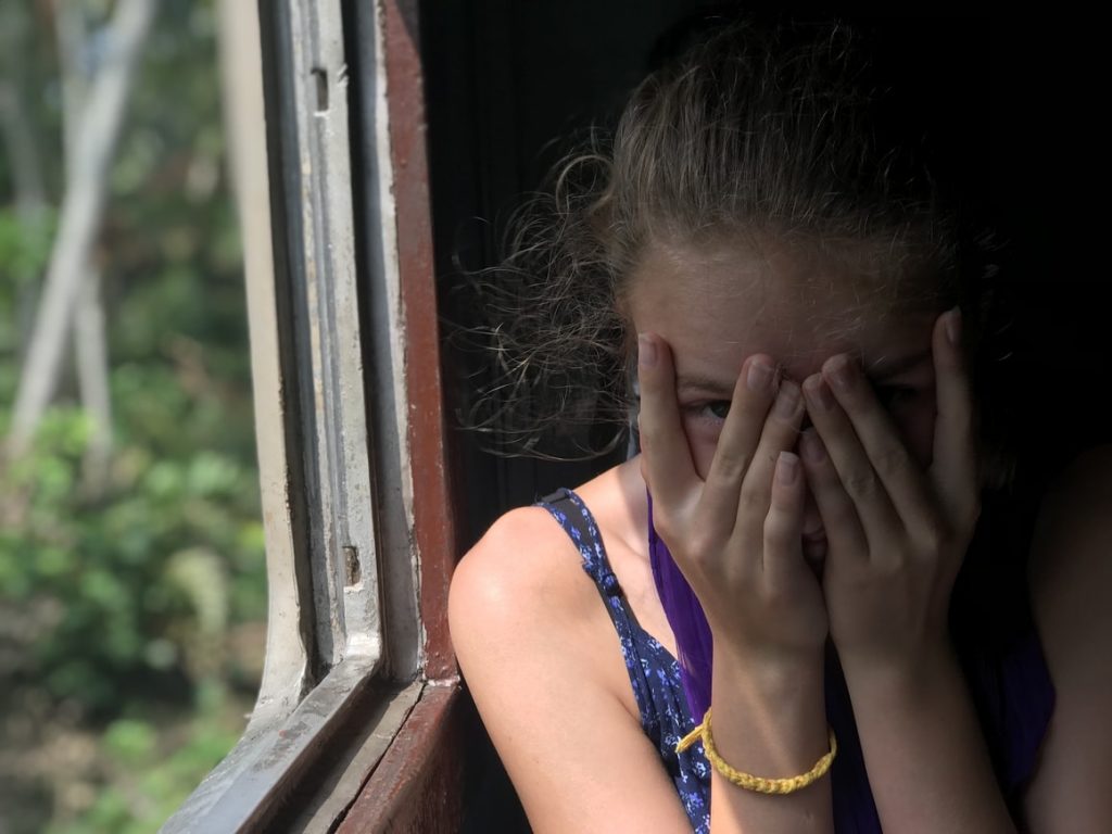 Girl covering her eyes on a train.