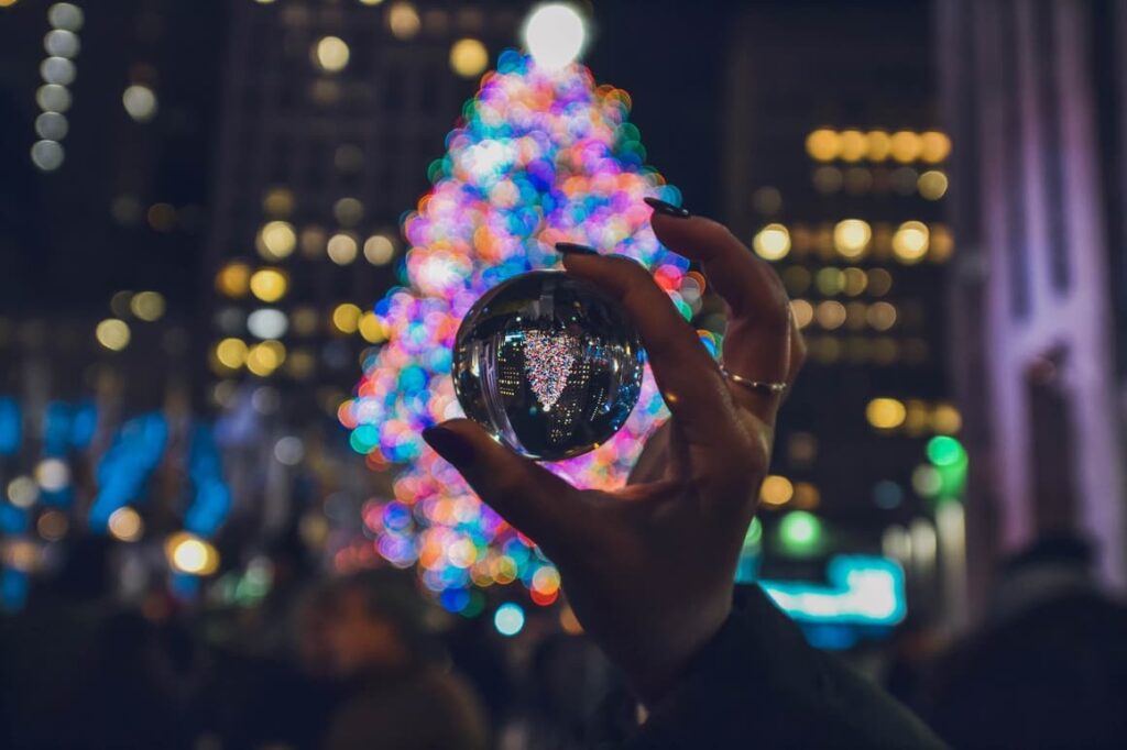 Woman holding a glass ball up to a Christmas tree in NYC