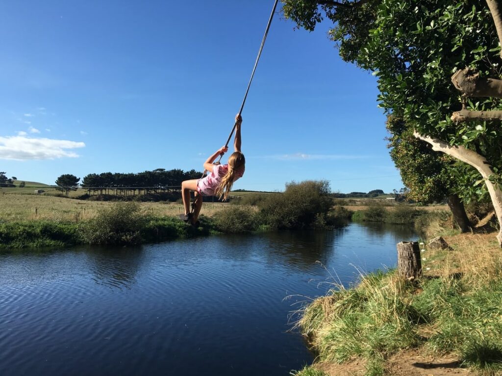 Girl swinging over water in new Zealand