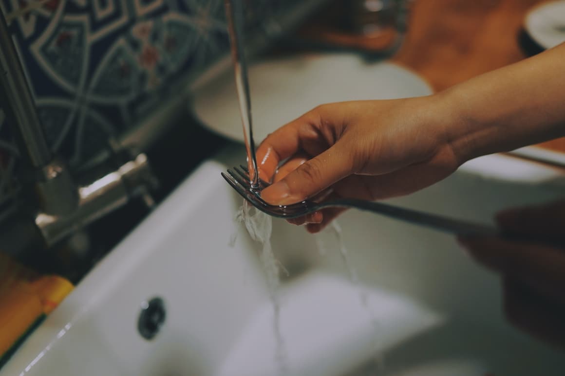 A person washing a fork. The key to successful homeschooling is doing the dishes in the Morning