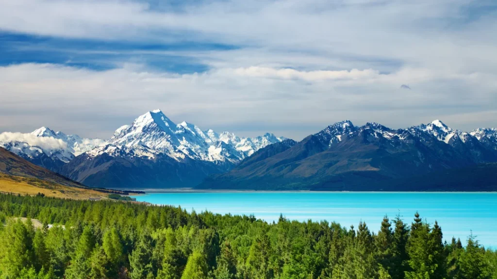 New Zealand snow capped mountains behind a beautiful blue lake 