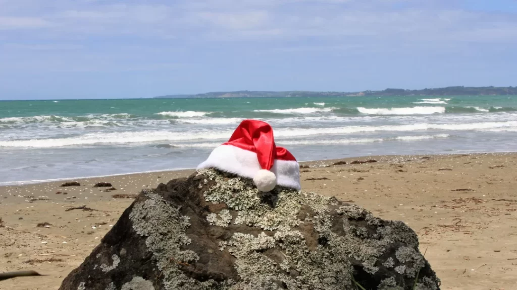 Christmas Santa hat on a rock on a beach in New Zealand. Is Christmas in New Zealand better?