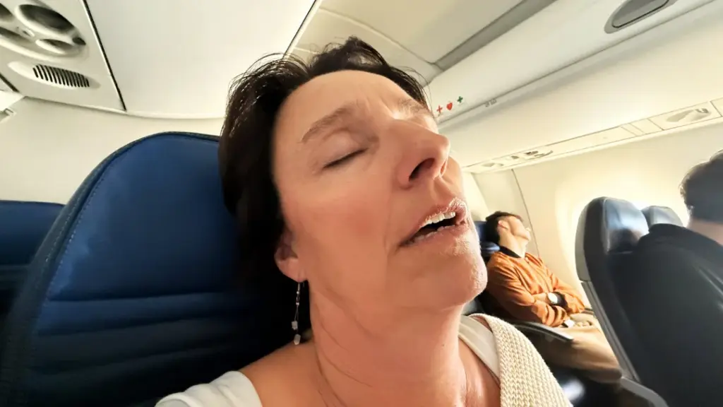 Woman asleep on a plane with her mouth open
