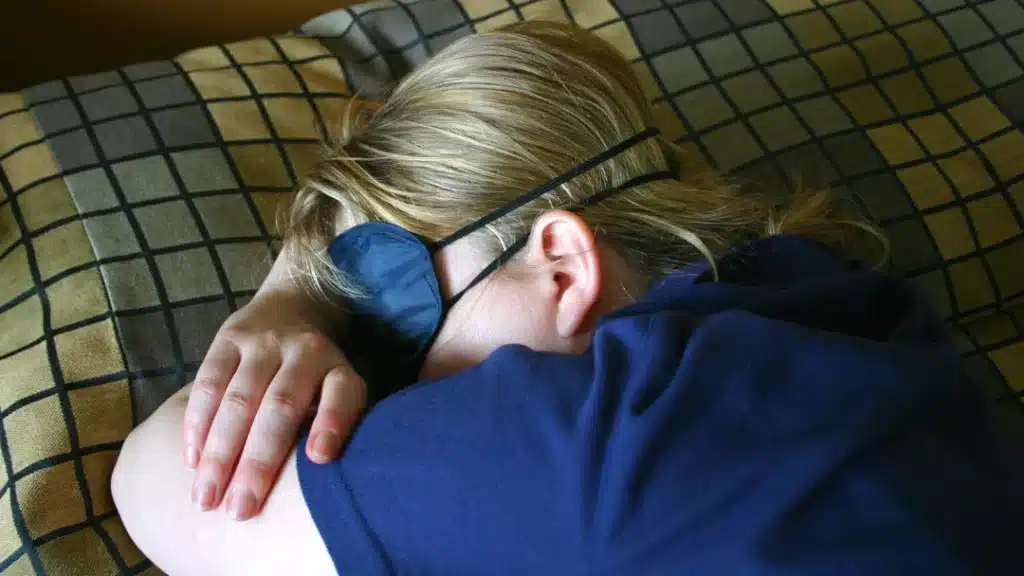 Boy sleeping with eye mask on after suffering from Jet lag after a long flight.