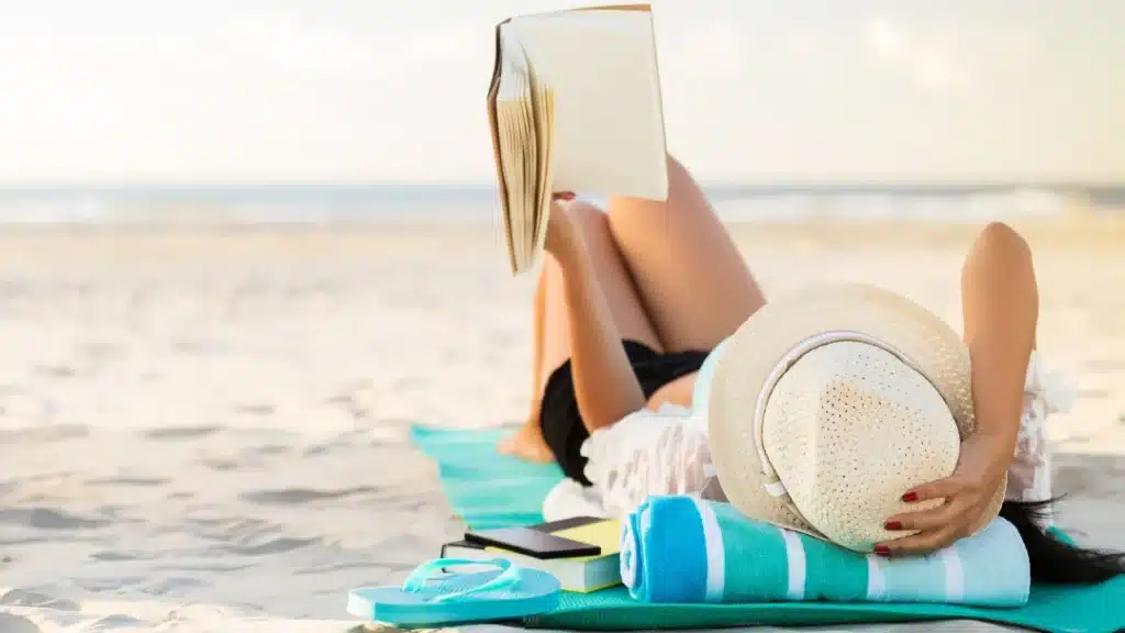 Woman on a beach reading a book about travel