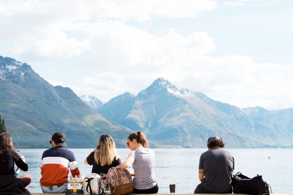 Group of people sitting by a lake in New Zealand. What are New Zealand people like?
