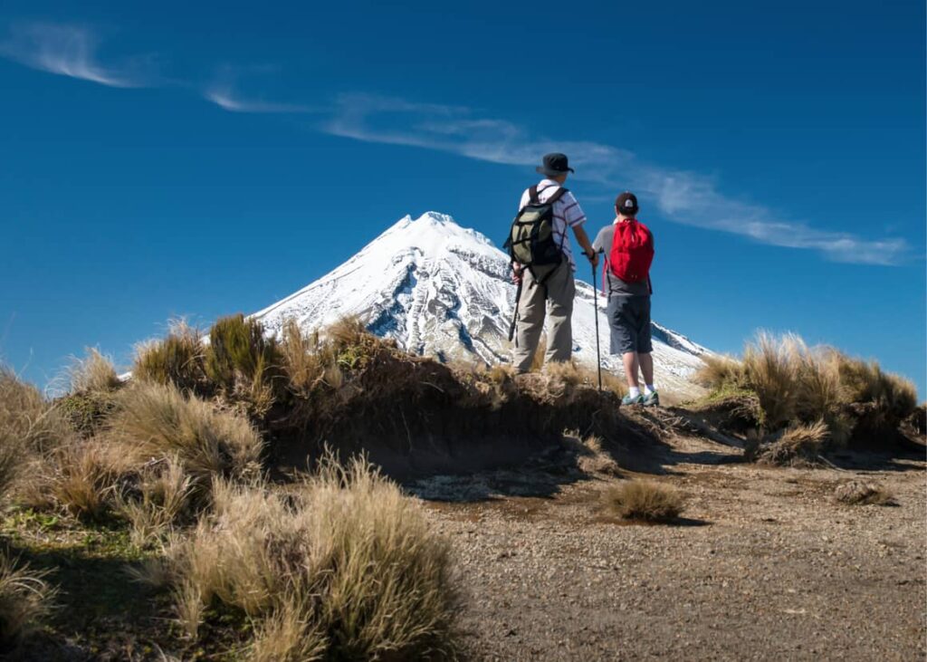 two people standing under a mountain in New Zealand. Fitting in in New Zealand